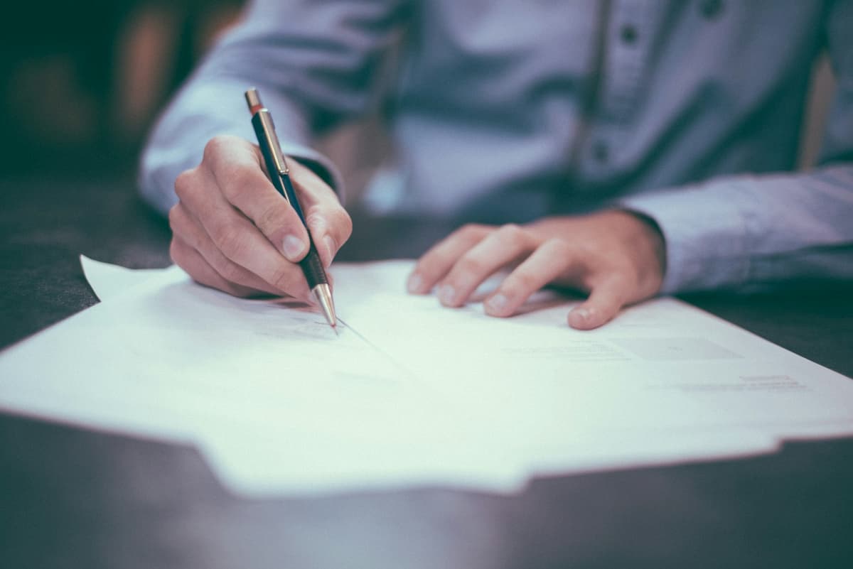 A person signing paperwork with a pen
